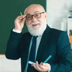 Uśmiechnięty starszy nauczyciel w okularach i garniturze trzyma długopis i marker.