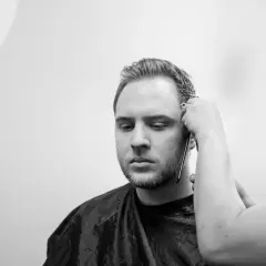 Un uomo con barba e basette viene tagliato. Diverse tipi di basette sono possibili, ma queste sono in fase di definizione.
