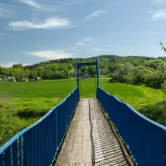 Mostek na szlaku trzech pogórzy prowadzi przez zielone pola i lasy.