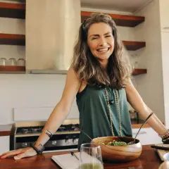 Glad kvinna i köket med en sallad, som hittat balans efter hormonell obalans.