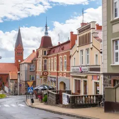 Ulica w gminie Skarszewy z kościołem w tle i kolorowymi kamienicami.