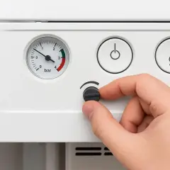 Dłoń kręci pokrętłem pieca, bo temperatura cwu nie rośnie. Manometr wskazuje niskie ciśnienie.