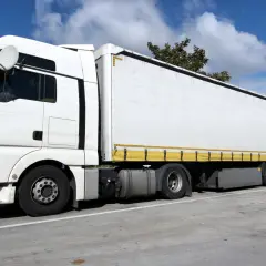 Ein weißer Lastzug mit großem Auflieger steht auf einem Parkplatz. Das ist ein typisches Beispiel, was ist ein Lastzug.