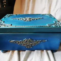 Elegancka, turkusowa skrzynia na skarby z ozdobnymi, złotymi ornamentami. Idealna do przechowywania cennych drobiazgów.
