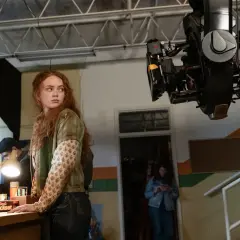 Na planie filmowym widać rudowłosą aktorkę, kamerę i co najmniej dwie osoby z ekipy technicznej pracujące przy realizacji jednego odcinka.