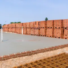 Frisch gegossener **fundamentbeton c25/30** wartet auf die Ziegelstapel, die daneben lagern.