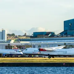 British Airways und Loganair Flugzeuge am London Flughafen. Im Hintergrund die markante Lyle's Golden Syrup Fabrik.