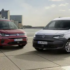 Dwa Volkswageny Caddy 3: czerwony osobowy i biały dostawczy, stoją na tle nowoczesnej architektury i wody.