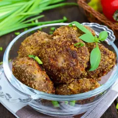 Chrupiące mielone z pieczarkami w szklanej misie, ozdobione listkami bazylii i szczypiorkiem. Obok pęczek zielonej cebulki i czerwone papryczki.