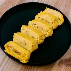 Tranches d'oeuf tamago, un délice japonais, disposées sur une assiette noire.