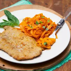 Escalope de veau panée, servie avec des tagliatelles de carottes et des feuilles de basilic. Une recette simple et savoureuse.
