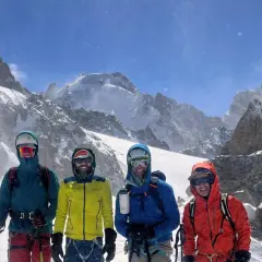 Czterech narciarzy w kolorowych kurtkach pozuje na tle ośnieżonych gór. To ich przygoda na trasie Haute Route.