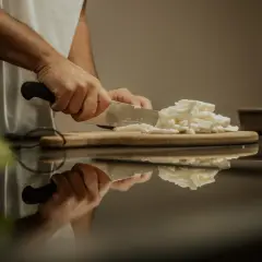 Hände schneiden Fior di Latte Mozzarella für eine Pizza.