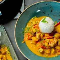 Ein köstlicher Thai Curry mit Tofu, Gemüse und Reis, garniert mit Frühlingszwiebeln und Chili.