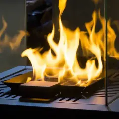 Flammen tanzen in einem modernen Kamin. Ein Pelletofen ohne Schornstein betreiben ist hier möglich, dank der Glasumrandung.