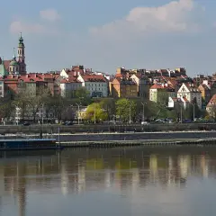 Widok na skarpa warszawska zapowiedzi, z kolorowymi kamieniczkami i zielenią, odbijającymi się w Wiśle.