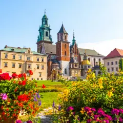 Krakowski Wawel, wpisany na **UNESCO listę polską**, w otoczeniu kwitnących kwiatów.