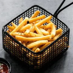Cesta negra llena de crujientes patatas fritas doradas, con un cuenco de salsa roja al lado.