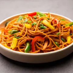 Un plato de espaguetis con verduras salteadas, con pimientos de colores y cebolleta.