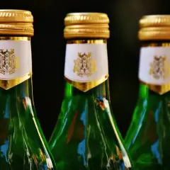 Trzy zielone butelki z złotymi nakrętkami i białymi etykietami z herbem. Czy to absynt? Co to jest?