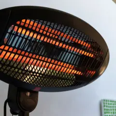 Lampada infrarossi terapia con elementi riscaldanti incandescenti arancioni dietro una griglia nera.