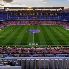 Widok na murawę i trybuny stadionu FC Barcelona Camp Nou. Słońce zachodzi nad stadionem.