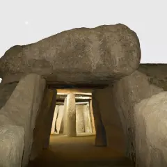 Entrada al dolmen de Menga, un túnel megalítico con pilares de piedra y una gran losa cubriendo la entrada.