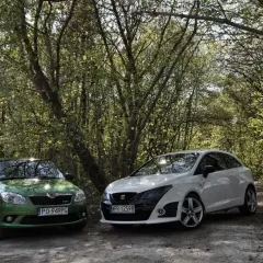 Zielony Skoda i biały Seat Bocanegra na leśnej drodze.