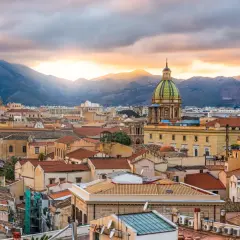Palermo pogoda marzec: zachód słońca nad miastem, góry w tle, kopuły i dachy kamienic.
