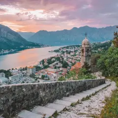 Escaleras de piedra con vistas a la bahía de Kotor al atardecer. Un lugar ideal donde viajar en julio barato.