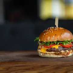 Apetyczny hamburger z sezamem na drewnianym blacie.