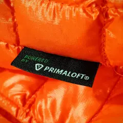 Pomarańczowa, pikowana tkanina z wszywką "Powered by Primaloft®". To materiał izolacyjny, który zapewnia ciepło.