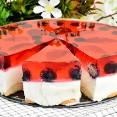 Letnie ciasto z truskawkami i galaretką, z kawałkiem już wyciętym, kusi świeżością i owocowym smakiem.