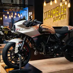 Una moto tipo scrambler color crema con detalles rojos y negros, lista para la aventura.