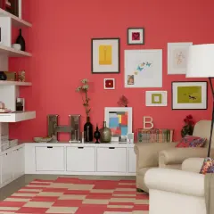 Wohnzimmer mit koralle farbener Wand, weißen Regalen, beigefarbenen Sesseln und einem Teppich mit roten und beigen Streifen.