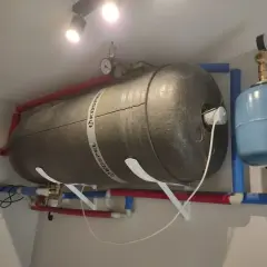 Duży bojler z rurami i niebieskim naczyniem przeponowym. Słychać bulgotanie w grzejniku, co może oznaczać potrzebę odpowietrzenia instalacji.
