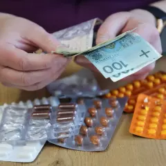 Dłonie liczą pieniądze nad lekami w blistrach. Możliwy zwrot za leki dla niepełnosprawnych.