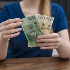 Dłonie trzymają banknoty: 100 zł i dwa 200 zł. To polskie "kosiniakowe" na drobne wydatki.