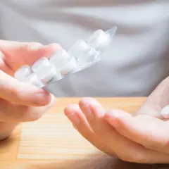 Dłoń trzyma tabletkę, a druga ręka blister. Czy to początek problemów z taurynian magnezu skutki uboczne?