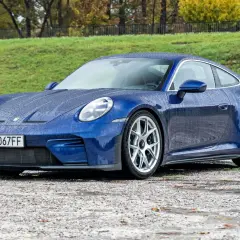 Niebieskie Porsche 911 na mokrej nawierzchni, z kroplami deszczu na karoserii. Czy to najtańsze porsche, jakie można znaleźć?