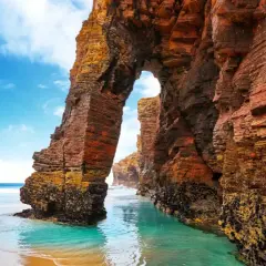 Arco natural en la playa de las Catedrales, un lugar ideal donde viajar en agosto en España.
