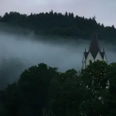 Mglisty poranek nad lasem, wieża kościoła wyłania się z mgły. Idealne miejsce na wycieczki ze Szczawnicy na Słowację.