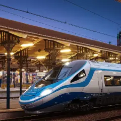 Nowoczesny pociąg EIP PKP Intercity na tle zabytkowego dworca w Gdańsku.