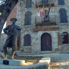 Estatua de un torero frente a la plaza de toros la ancianita. El edificio de piedra tiene un letrero y banderas españolas.