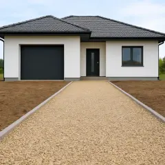 Nowy podjazd z kruszywa przed białym domem z garażem. Zastanawiasz się, ile kosztuje tona kruszywa na podjazd?