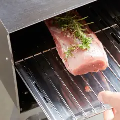 Un filet mignon fumé prêt à être cuisiné, assaisonné d'herbes et de poivre, est placé dans un fumoir. Une recette savoureuse en perspective.