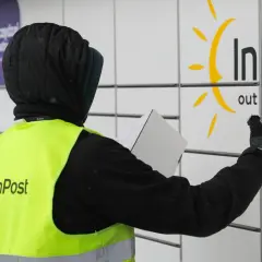 Pracownik w kamizelce InPost z paczką przy paczkomacie. Czy muszę naklejać etykietę InPost? Nie, wystarczy kod nadany przez system.