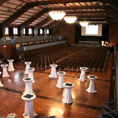 Innenansicht der Stadthalle Herrenberg mit vielen Sitzreihen, einer Bühne und Stehtischen, bereit für eine Veranstaltung.