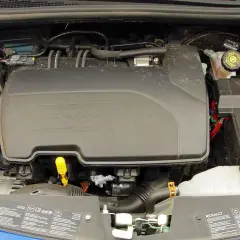 Silnik Renault Clio 3, widok z góry. Widać plastikową osłonę silnika, zbiorniczek płynu chłodniczego i inne elementy.