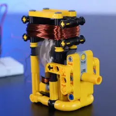 Model z klocków pokazuje, jak wytworzyć prąd z magnesu. Wirująca cewka miedziana nad magnesem generuje energię.